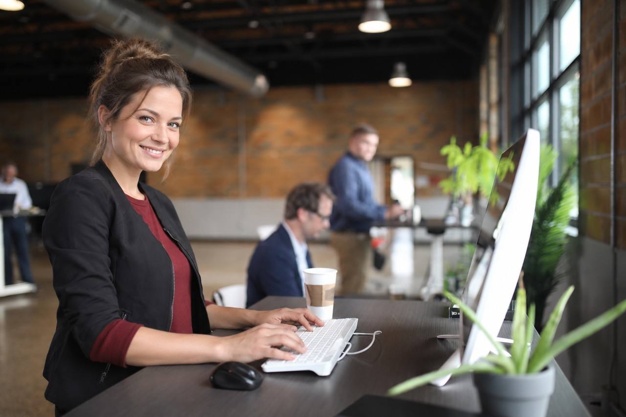 Woman smiling while working at a desk in a coworking space